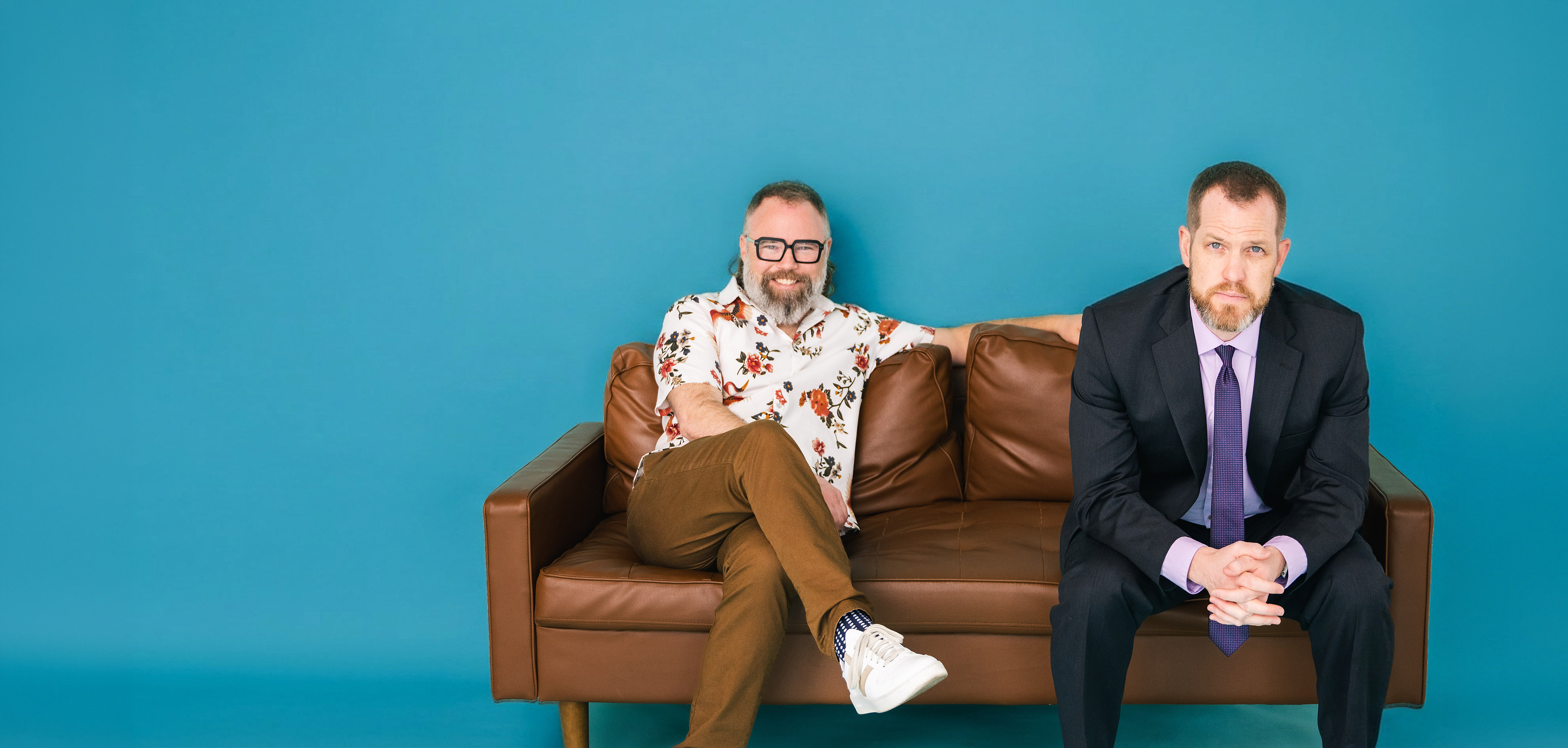 Dan McClellan and Dan Beecher sitting on a couch against a blue wall